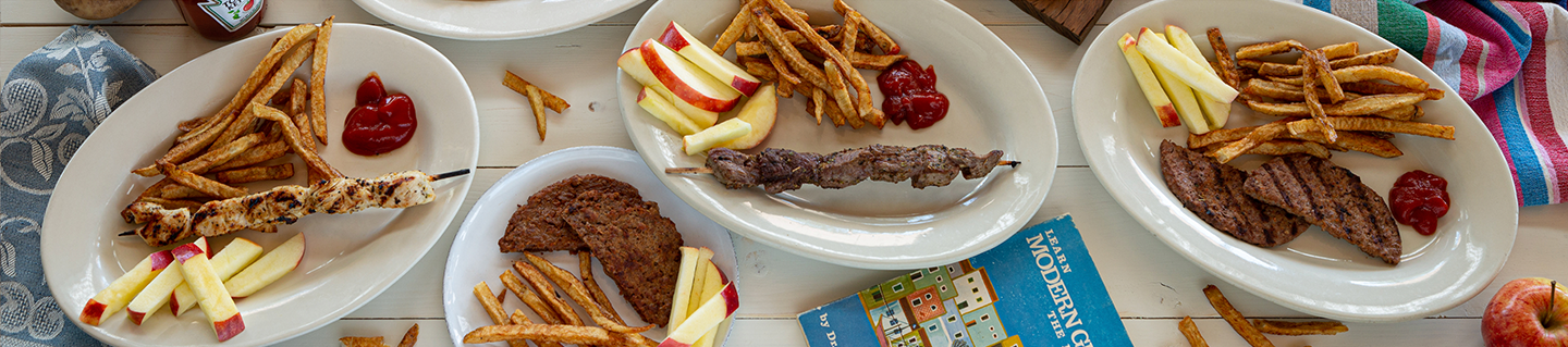 Three kids' plates with fresh-cut fries, apple slices and skewers