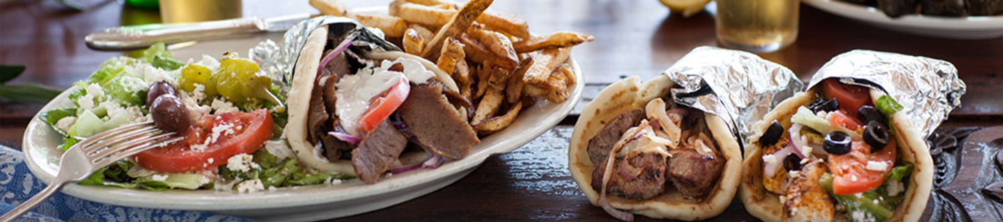 Greek salad, gyro plate and pita wraps on a table